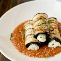 3 slices of eggplant rolled up and filled with ricotta served on a bed of tomato sauce