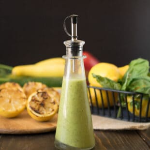 A side view of lemony green salad dressing in a glass bottle