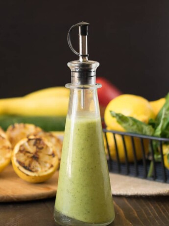 A side view of lemony green salad dressing in a glass bottle