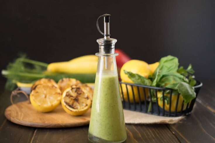 A side view of lemony green salad dressing in a glass bottle