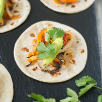 Grilled pork tenderloin fajitas are a quick and easy way to get a summer meal served in under 30 minutes. Marinated pork tenderloin is grilled along with onions and peppers. The pork is sliced then all are served on warm tortillas garnished with fresh avocado and cilantro.