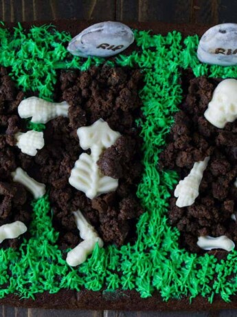 3 graves cut out of a brownie with white chocolate skeletons buried