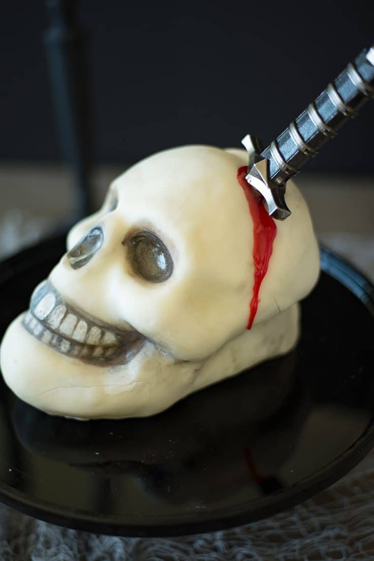 The side of the skull cake showing the dagger sticking out and the faux blood dripping out made from gel food coloring