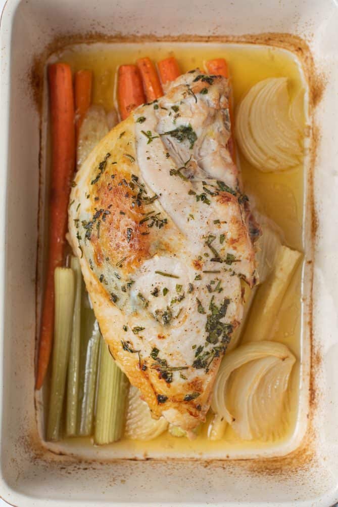 A half turkey breast coated with herbs roasted on a bed of carrots, celery, onion, parsnip and garlic