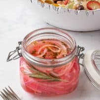 A jar filled with Herbed Pickled Red Onions