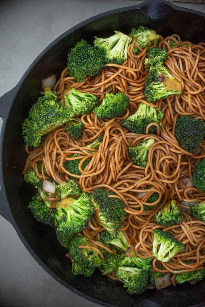 A cast iron skillet filled with noodles and broccoli