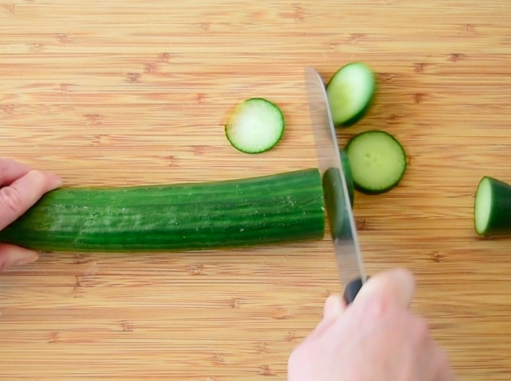 Slicing a cucumber on a bamboo cutting board