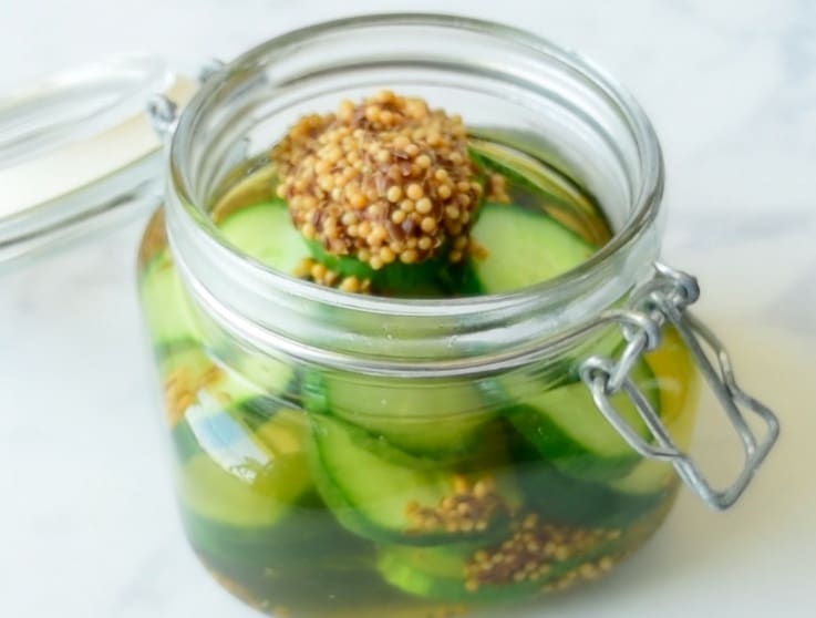Adding the pickle chips, vinegar, dill and spices to a poptop jar