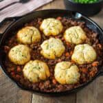 A pan of minced beef and carrots topped with crispy dumplings