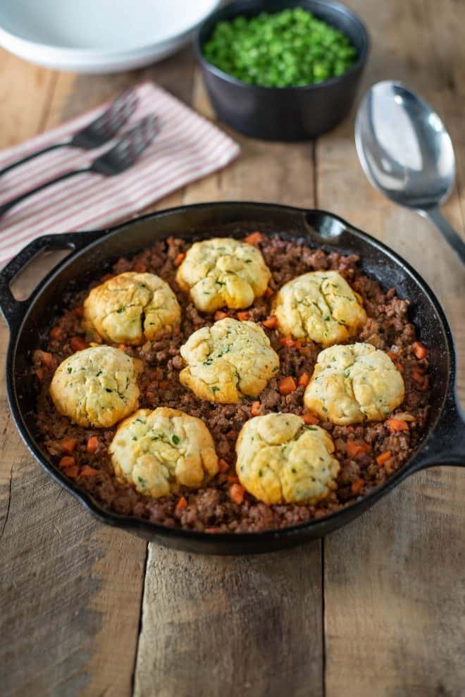A cast iron skillet with minced beef and dumplings