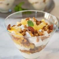 Layers of yogurt with granola and pineapple in a glass bowl