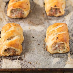 4 sausage rolls on a baking sheet fresh out of the oven