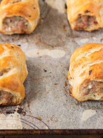4 sausage rolls on a baking sheet fresh out of the oven