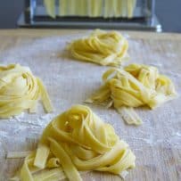 Mounds of homemade tagliatelle pasta on a cutting board