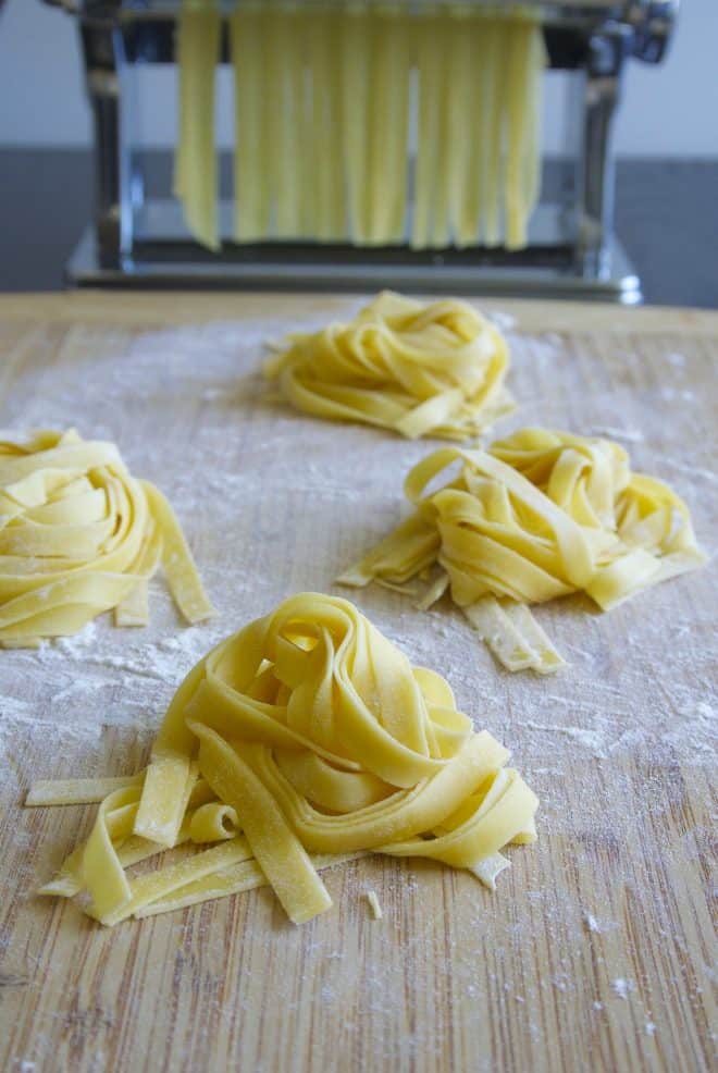 Mounds of homemade tagliatelle pasta on a cutting board