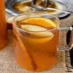 A clear mug of hot apple cider