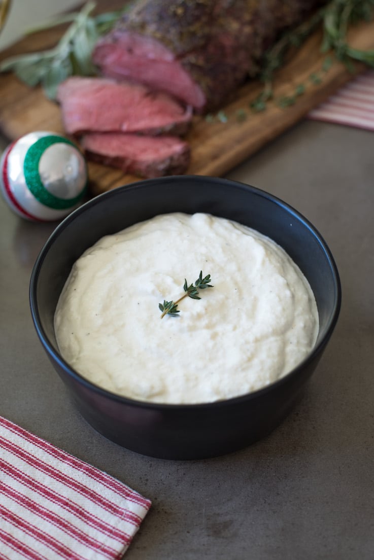 Horseradish sauce served in a black bowl with beef tenderloin in the background