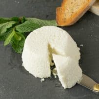 A knife cutting into homemade ricotta