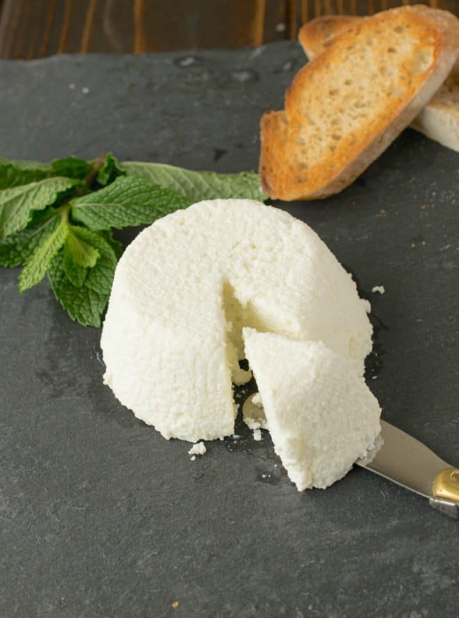 A knife cutting into homemade ricotta