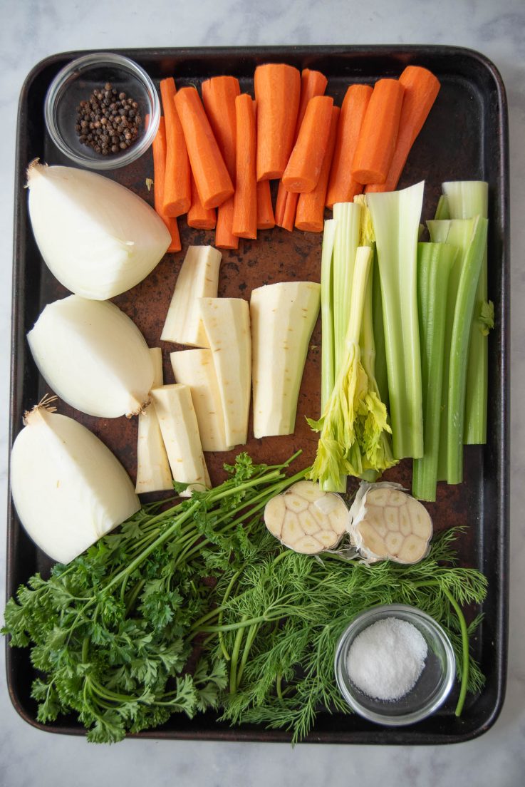 A tray of vegetables and herbs for chicken broth