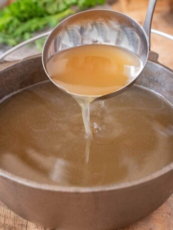 Pouring broth from a ladle into a pan