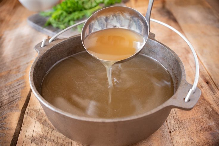 Pouring broth from a ladle into a pan