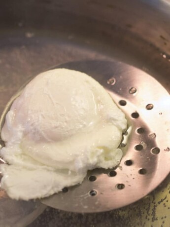 Using a slotted spoon to remove a poached egg