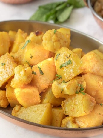 Potatoes and cauliflower seasoned with spices garnished with fresh mint
