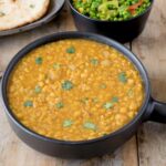 A black bowl filled with Indian dal
