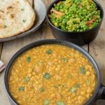 A bowl of Indian dal with naan bread and Indian spiced peas