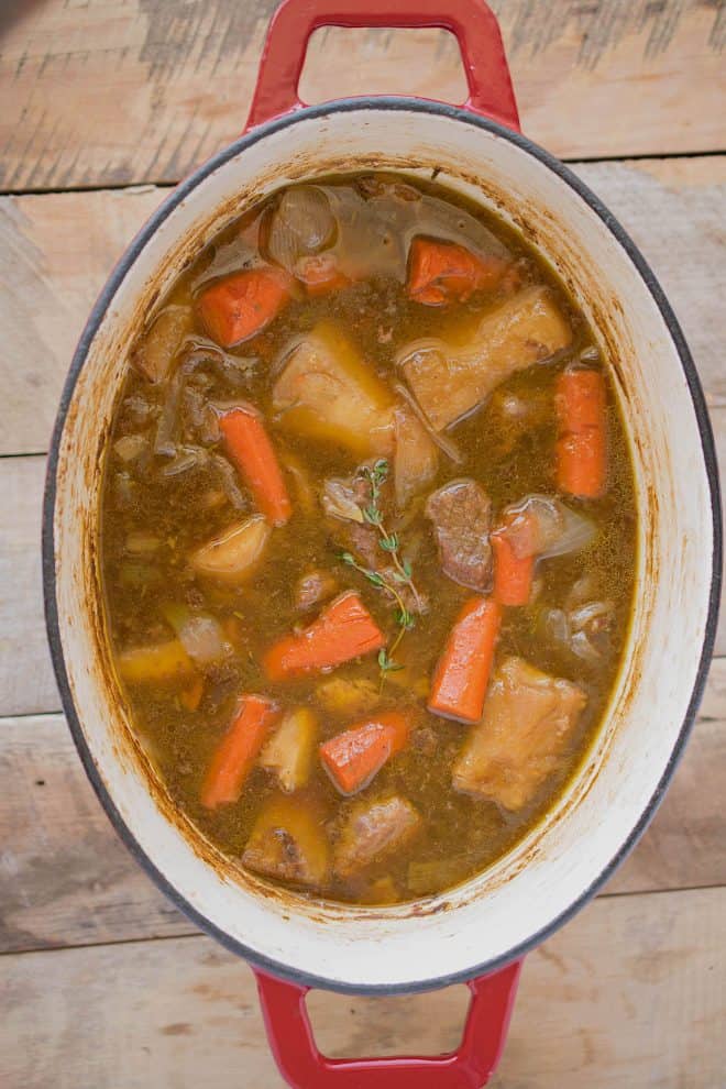 Large pieces of beef, carrots and vegetables in beef stew cooking in a pan