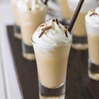 A closeup of a shot glass with Irish coffee milkshake topped with whipped cream