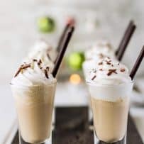 Shot glasses viewed from the side showing the layering of Irish coffee milkshake and whipped cream