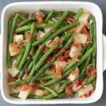 An overhead view of a pan of green beans with potato and tomato