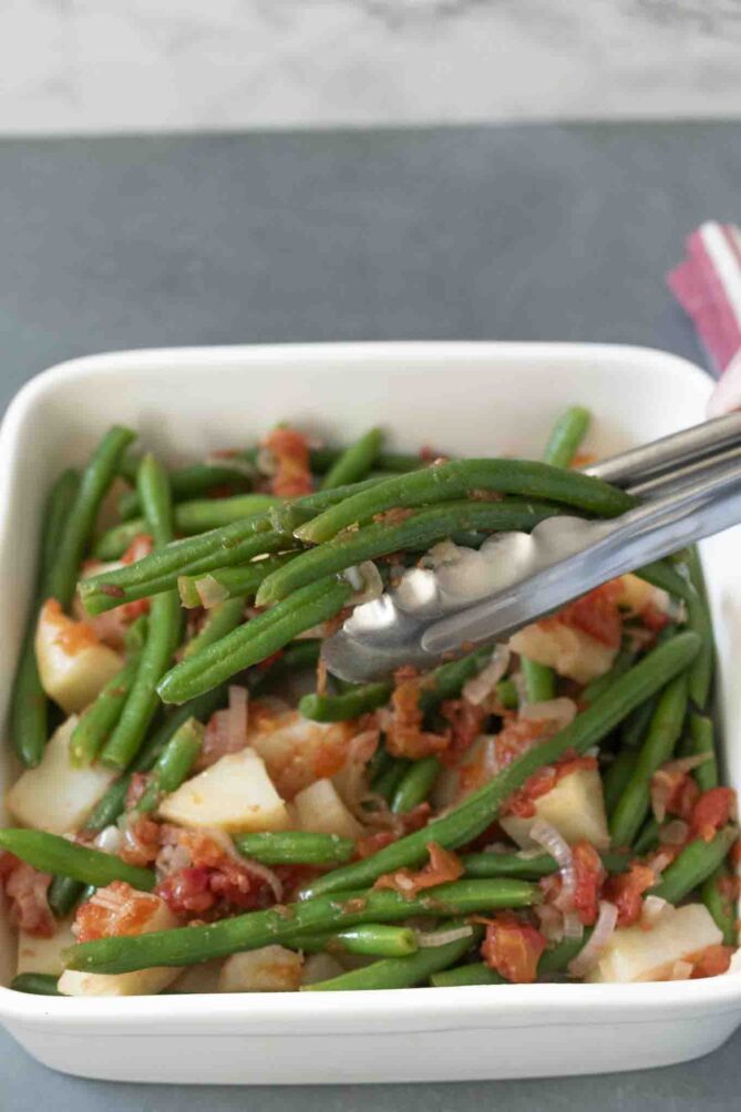 Using tongs to lift green beans