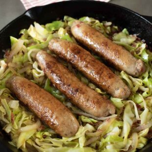 Italian sausage and cabbage cooking in a frying pan