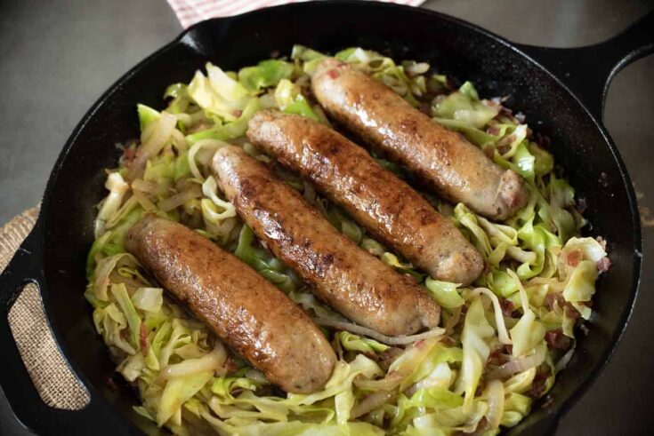 Italian sausage and cabbage cooking in a frying pan