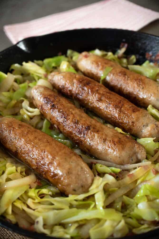 4 Italian sausages lined up on top of cabbage