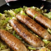 Browned sweet Italian sausage served in a cast iron skillet with cabbage