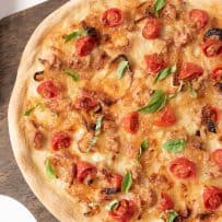 Italian sausage and caramelized onion pizza from overhead on a wood board