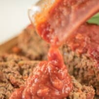 Pouring marinara sauce onto meatloaf