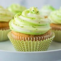 Key lime cupcakes on a cake stand in green and white striped cups