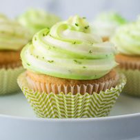 A key lime cupcake in a striped green and white muffin cup