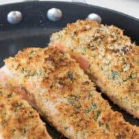 A closeup of breaded salmon cooking in a pan