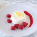 Lemon panna cotta garnished with lemon and raspberry sauce