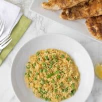 A bowl of risotto with peas and chicken breasts
