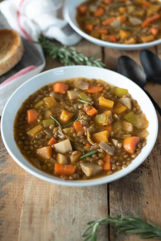 A large white bowl filled with lentil soup and vegetables
