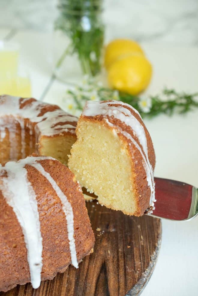 Lifting a slice of limoncello pound cake from a whole bundt cake