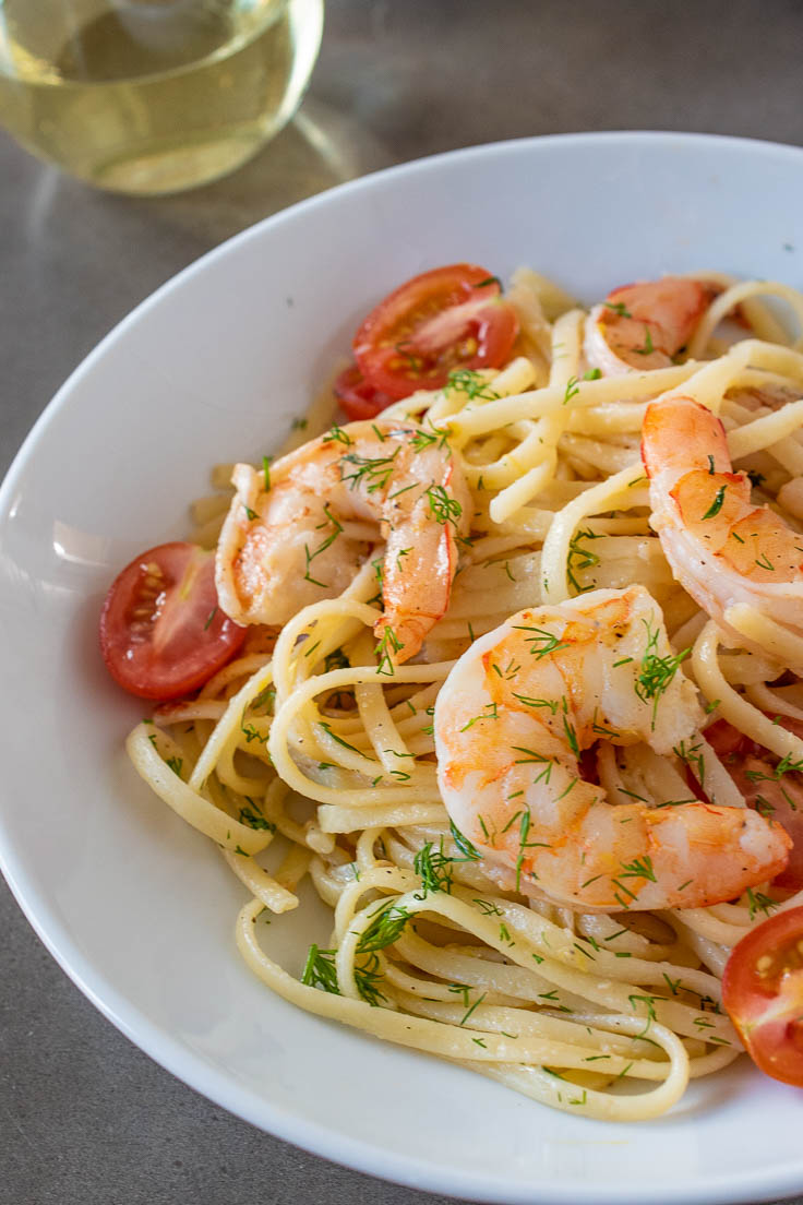A closeup of the juicy shrimp and linguine garnished with green dill