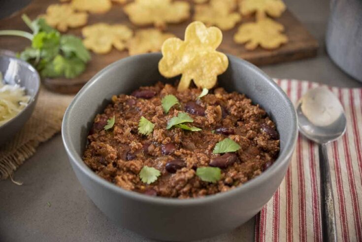 Meaty chili with beans in a grey bowl with a shamrock shaped tortilla chip